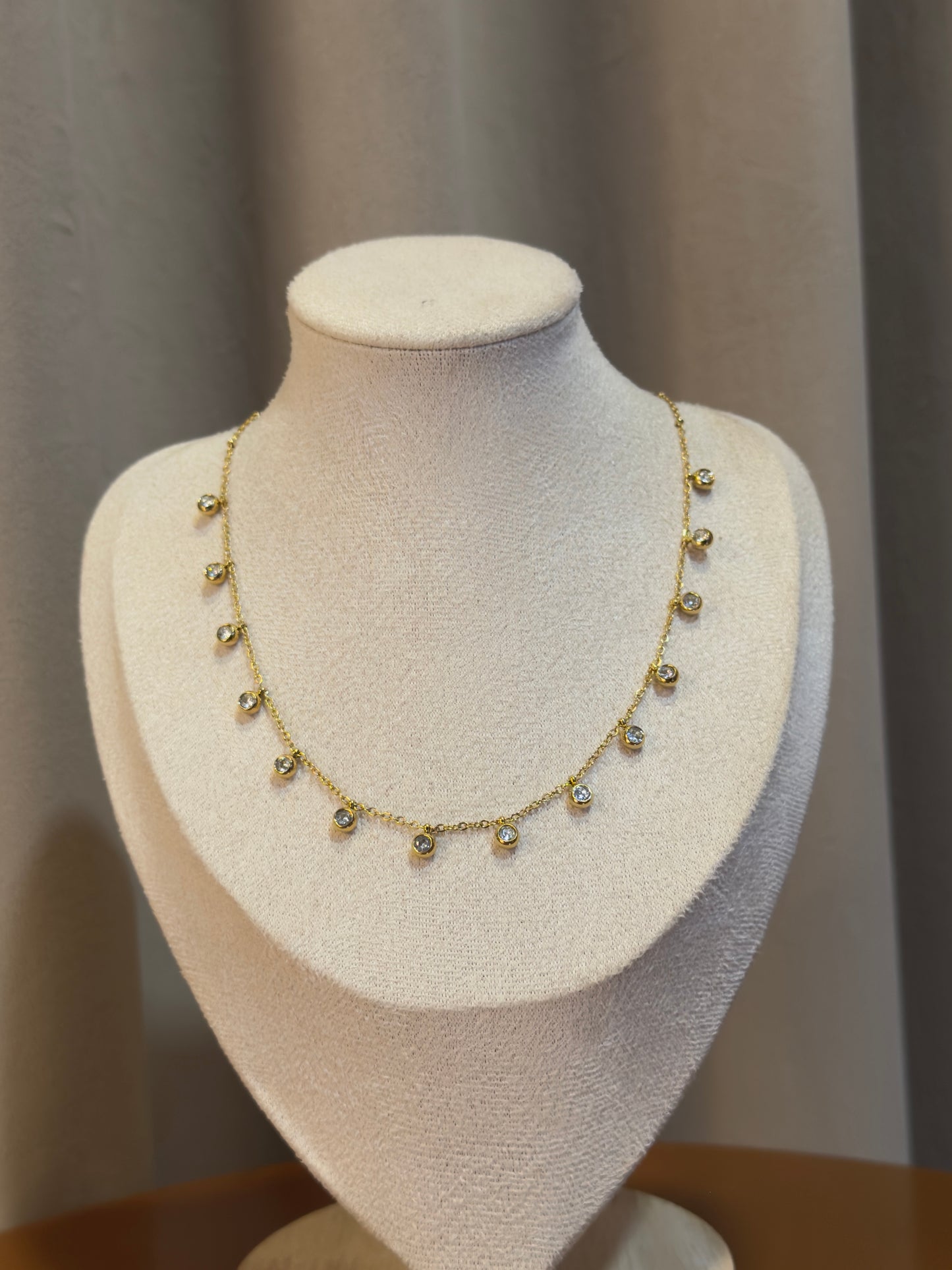 Gold necklace on a mannequin bust against a neutral background