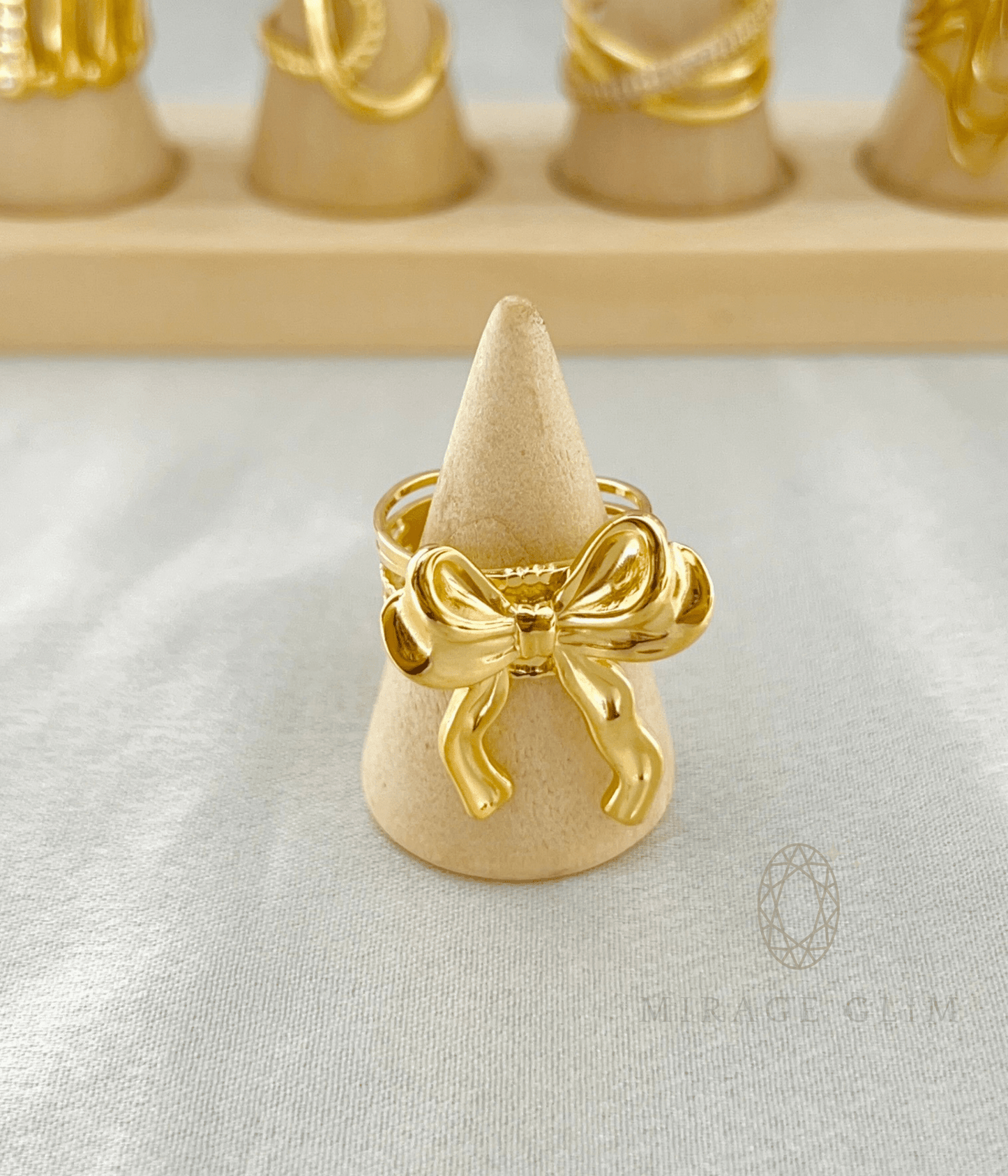 Minimal gold bow ring displayed on a wooden ring stand with a polished finish