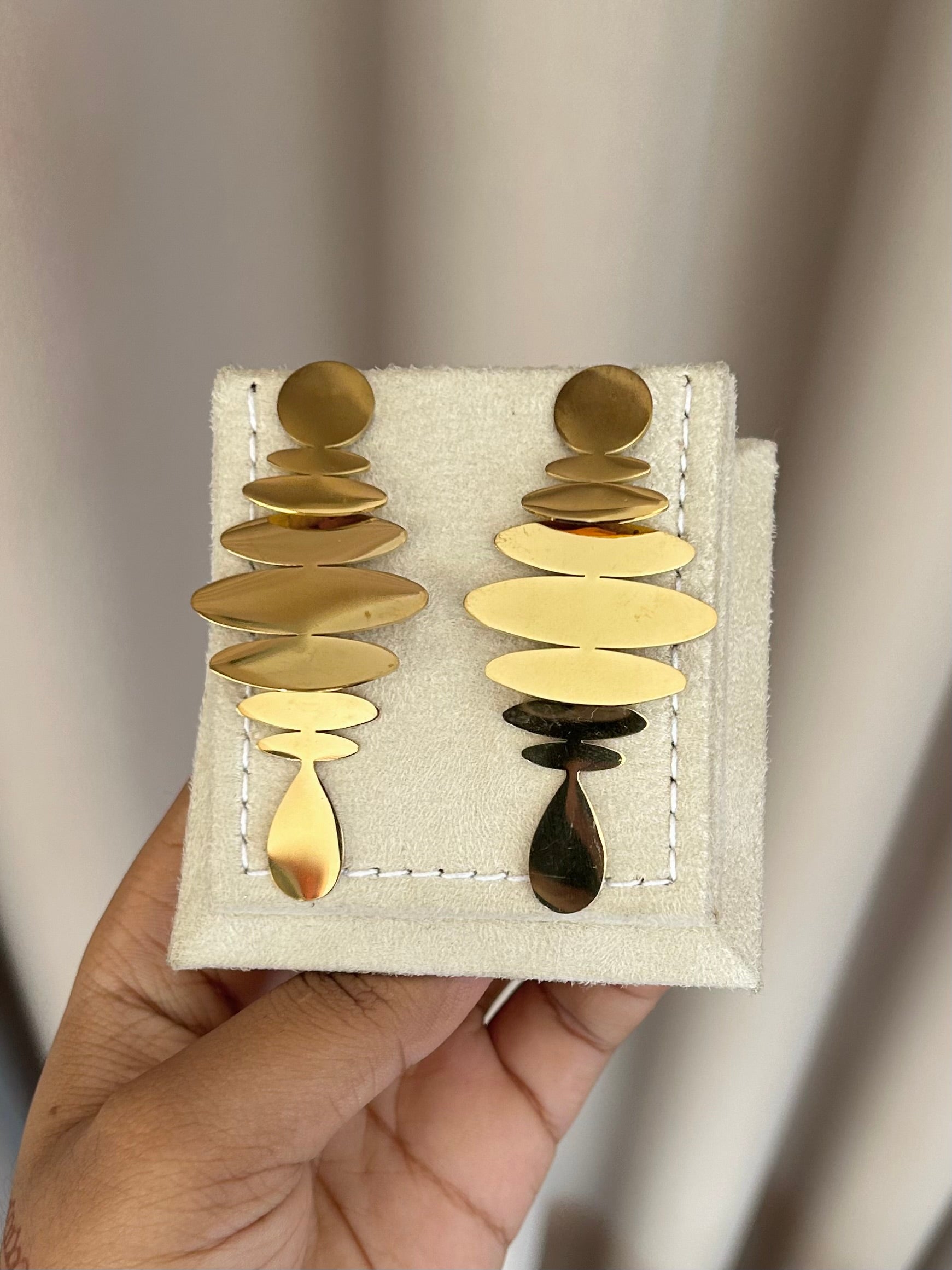 Gold stacked disc earrings on display stand