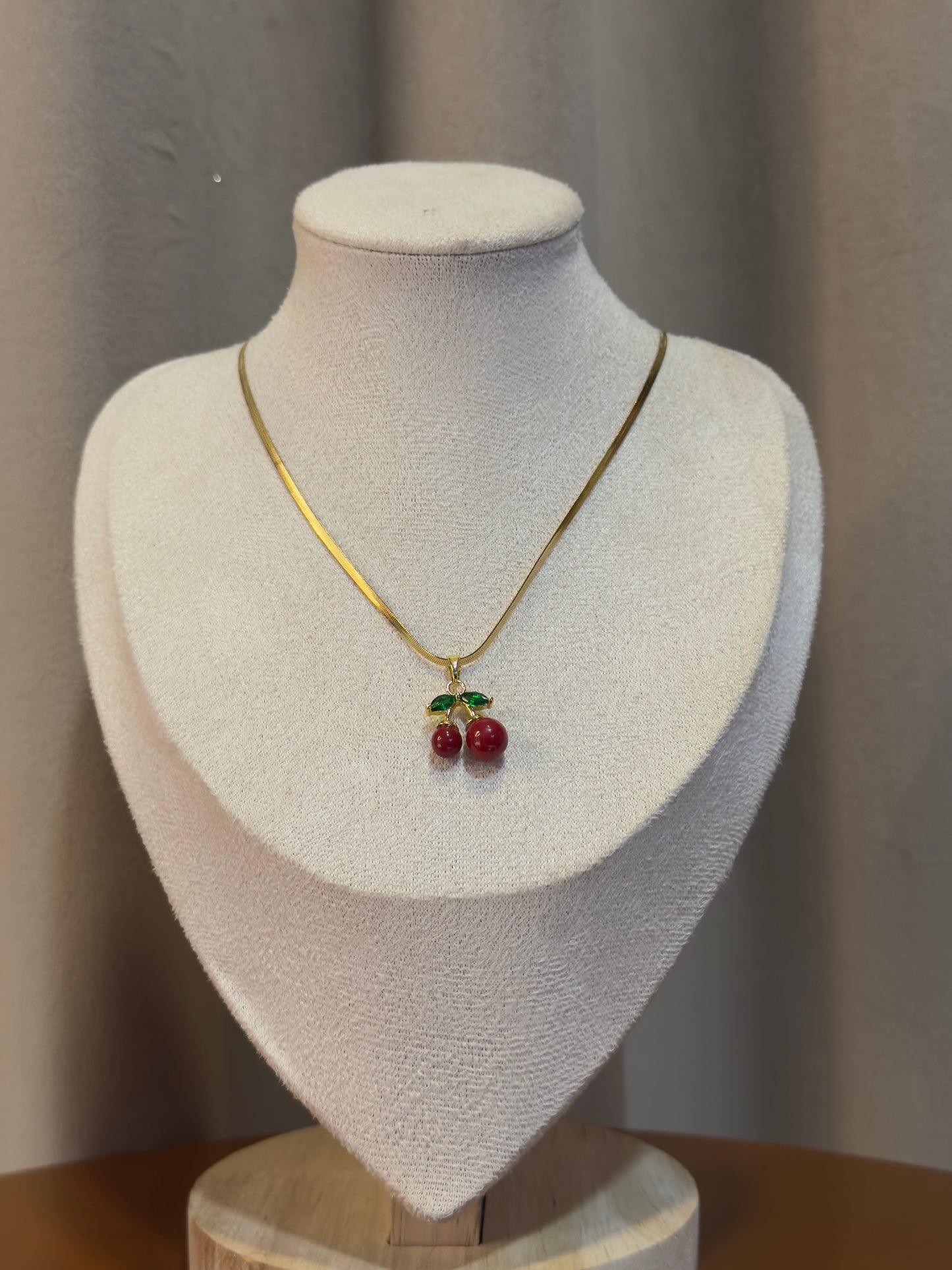Gold anti-tarnish necklace featuring a cute red cherry pendant with green leaf accents on a sleek gold chain.