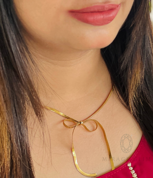 Gold bow tie necklace worn on neckline with elegant minimal design