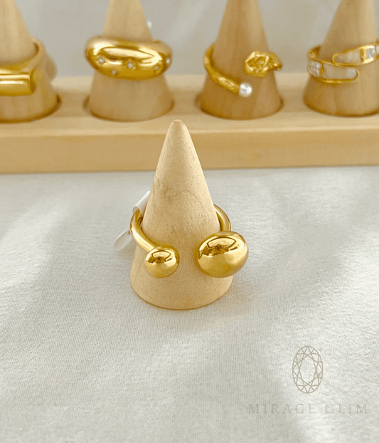 Open band ring with smooth golden globe ends in minimal design.
