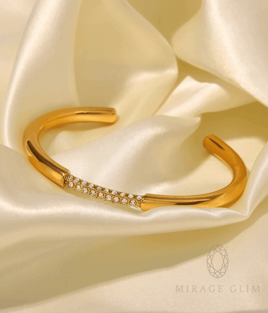 Adjustable gold bangle with delicate crystal detailing on soft satin background