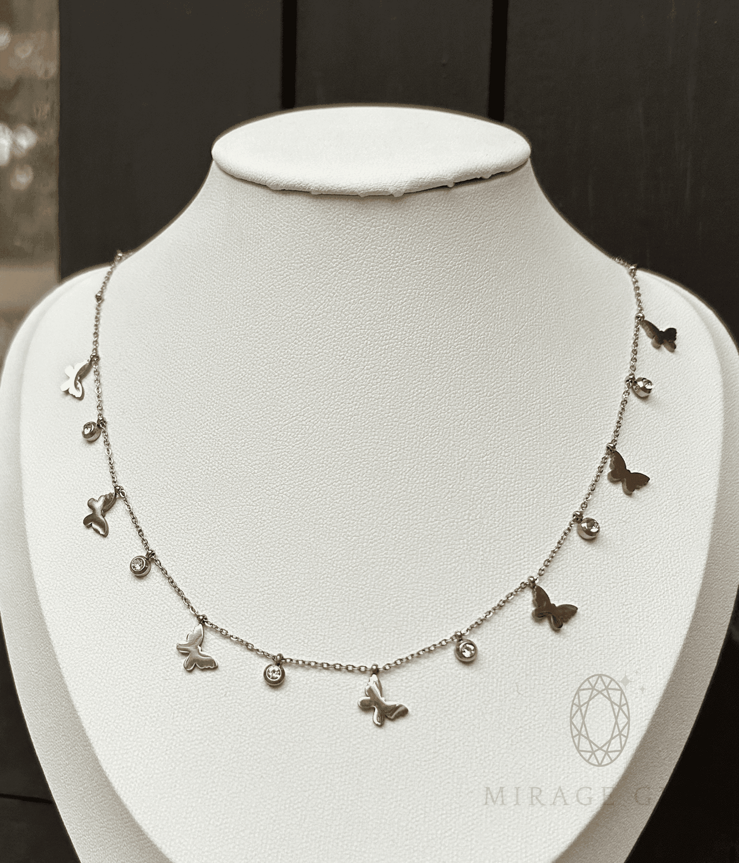 Silver butterfly necklace with delicate stones on a fine chain displayed on a white bust
