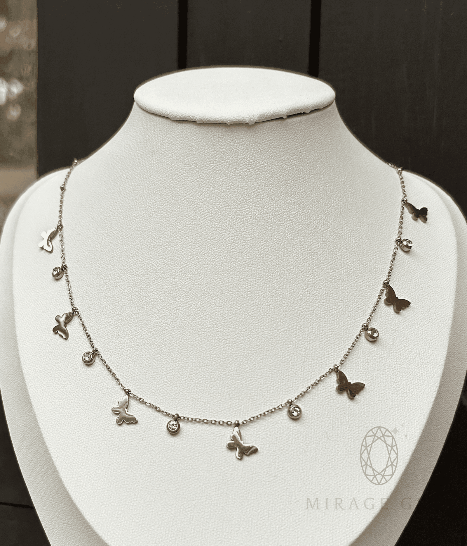 Silver butterfly necklace with delicate stones on a fine chain displayed on a white bust
