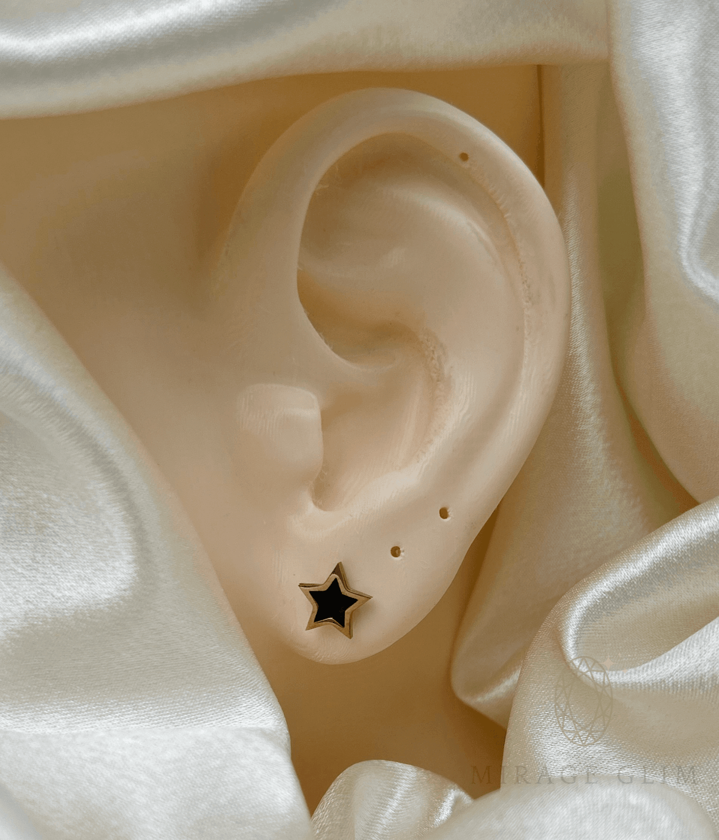 Minimal star-shaped stud earring on ear with elegant fabric backdrop
