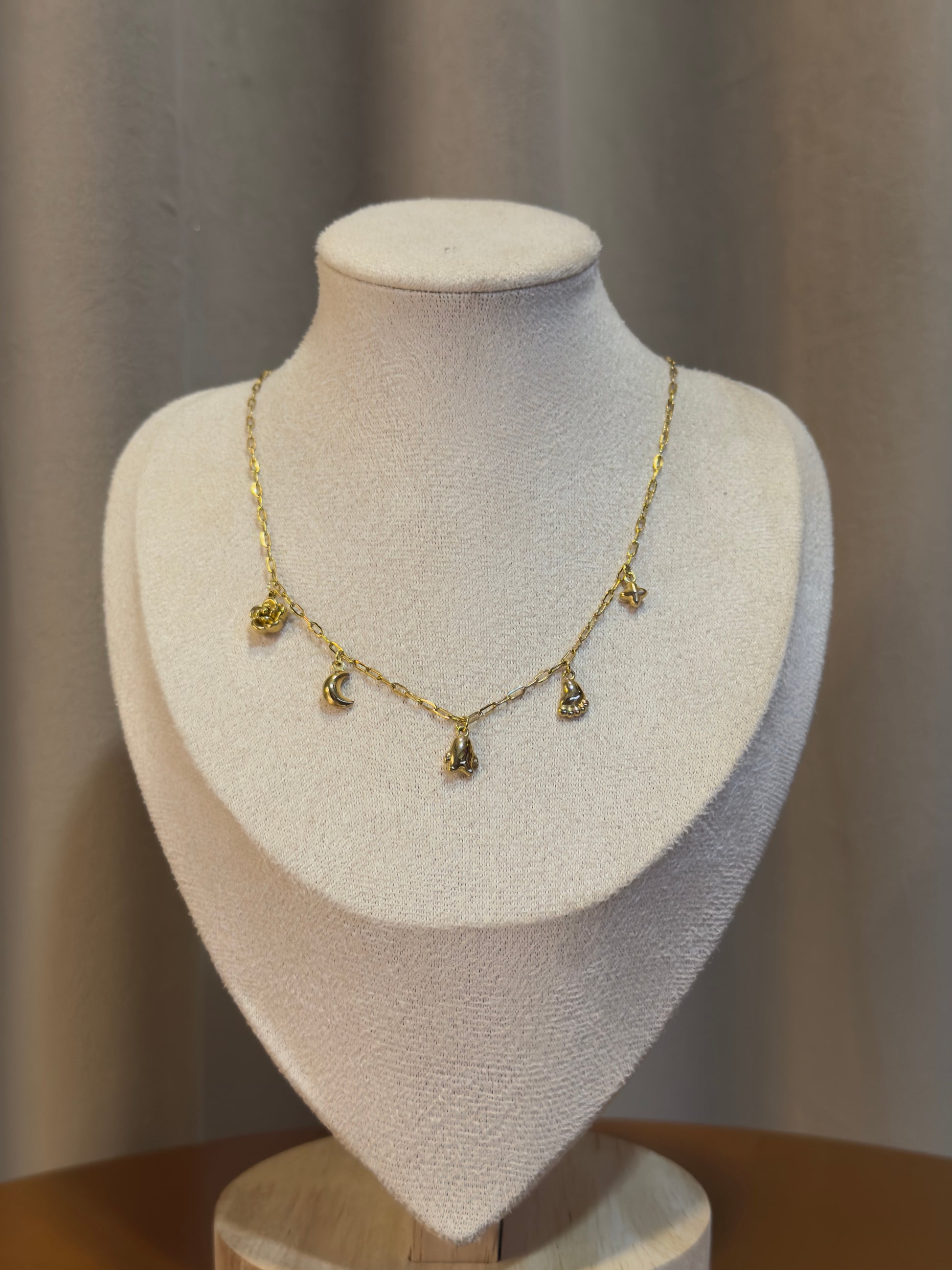 Gold necklace with charms on a mannequin bust against a neutral background