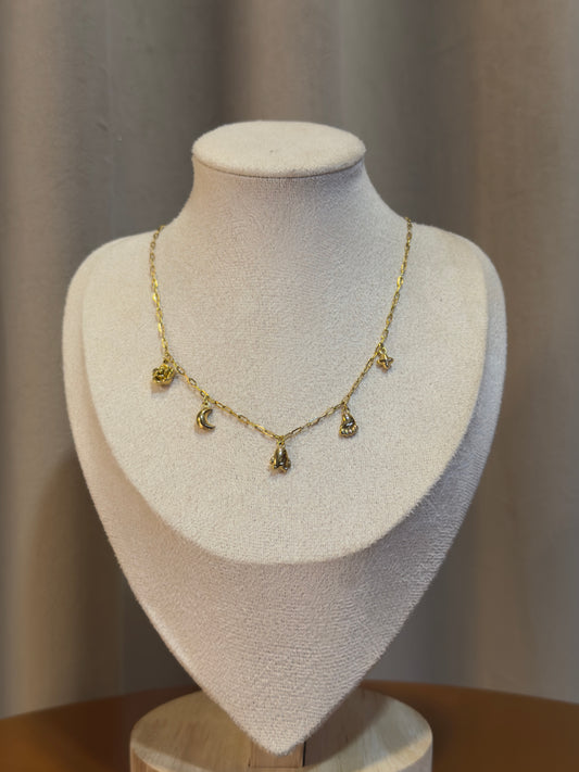 Gold necklace with charms on a mannequin bust against a neutral background