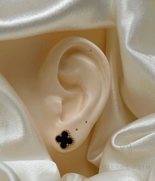 Elegant clover-shaped stud earring on ear with ivory fabric backdrop