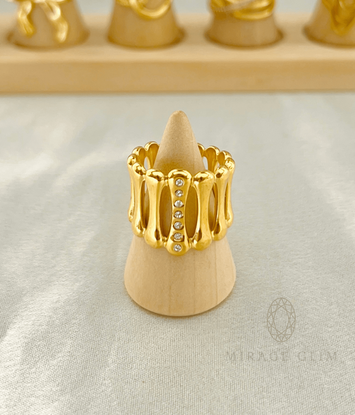Bold gold statement ring with crystal accents displayed on a wooden ring stand