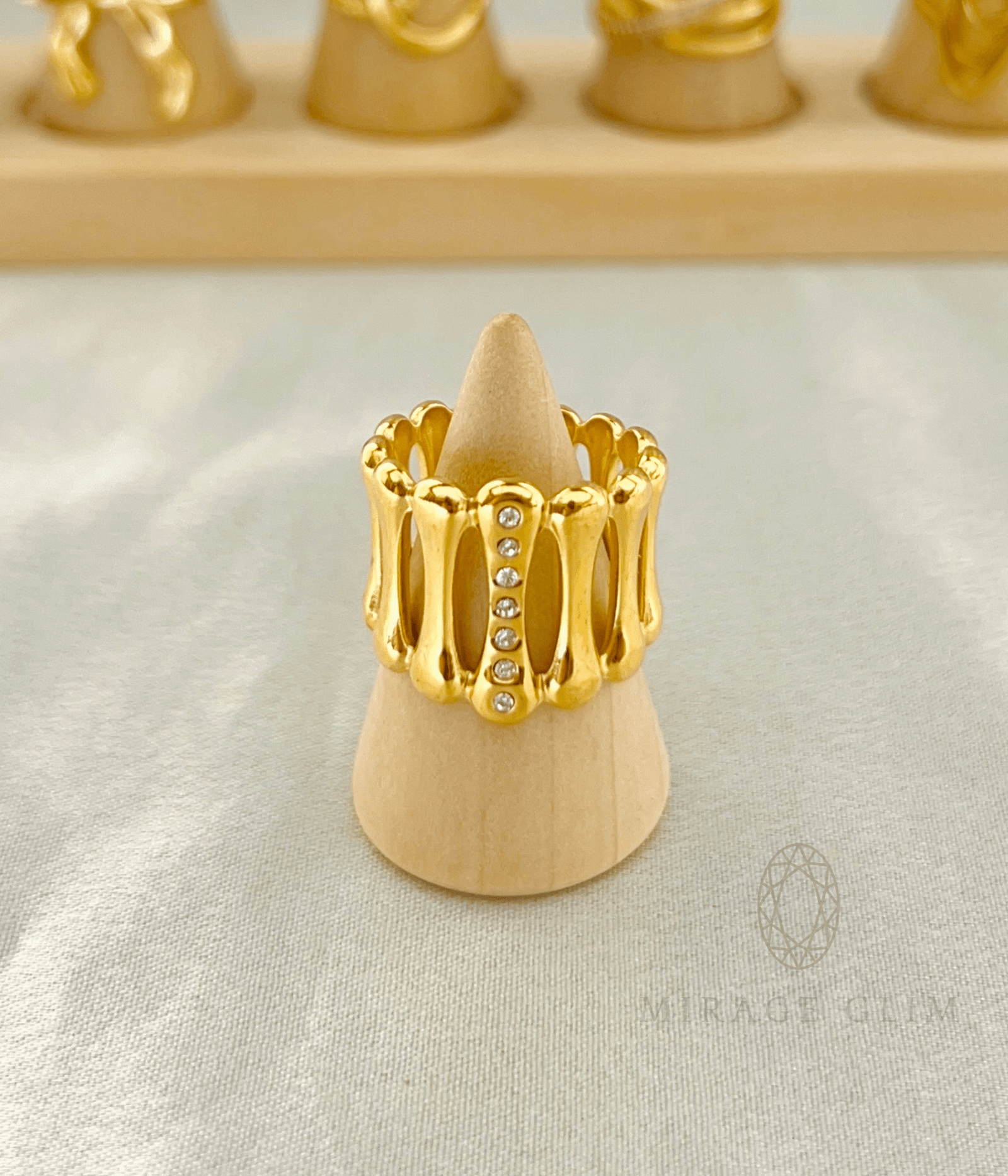 Bold gold statement ring with crystal accents displayed on a wooden ring stand